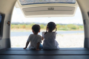 車で子供が2人座ってる外を見てる様子