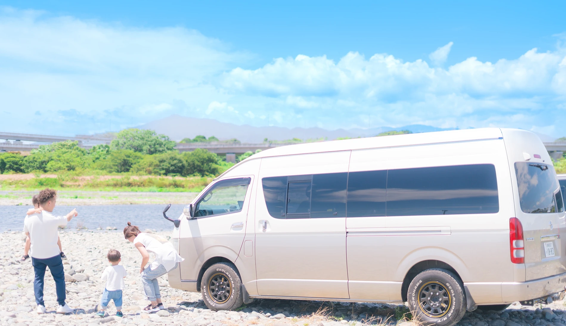 川沿いで車から降りた家族が遊んでる様子